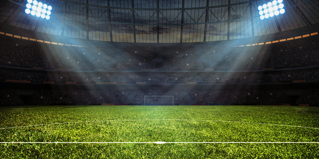 A football stadium where the stadium lights are shining down on the turf