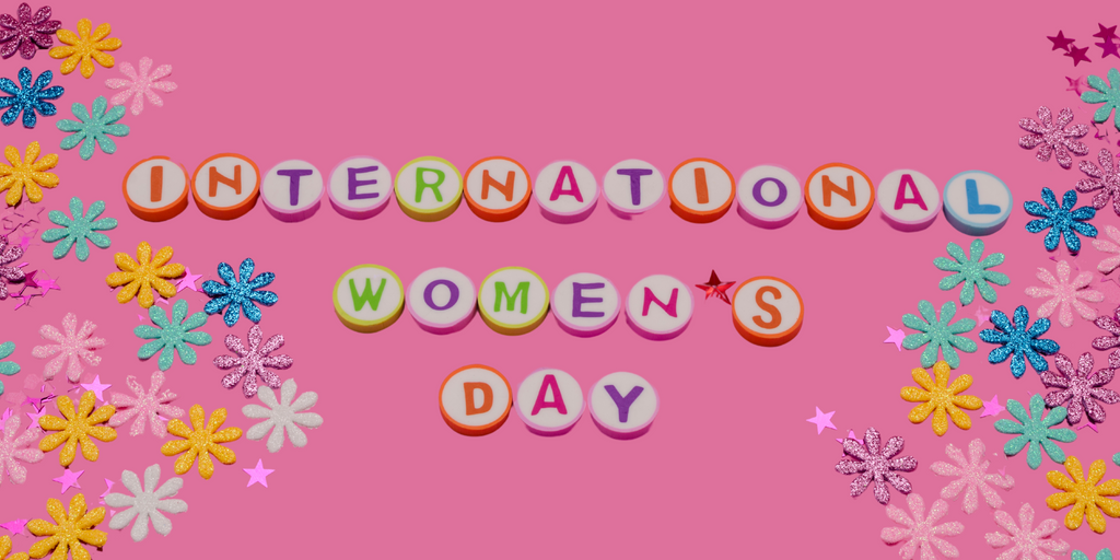 Colorful letters spell 'INTERNATIONAL WOMEN'S DAY' on pink, with glittery flowers and stars around