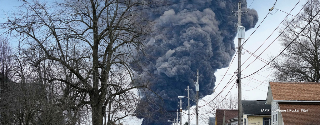 A large plume of grey smoke from derailed train cars in East Palestine, Ohio.